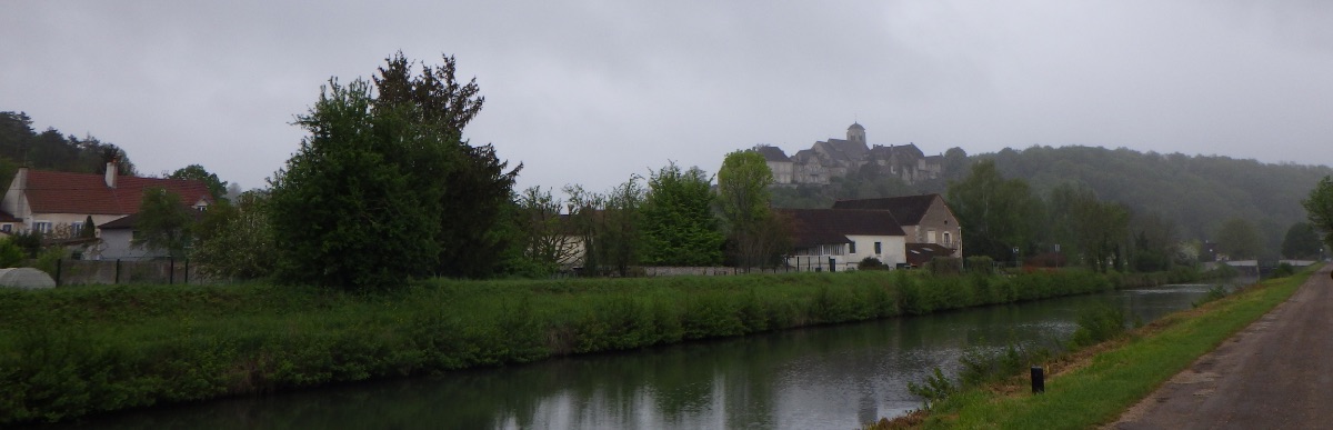 Grijze luchten en regen, kanaal met dorpje in de verte